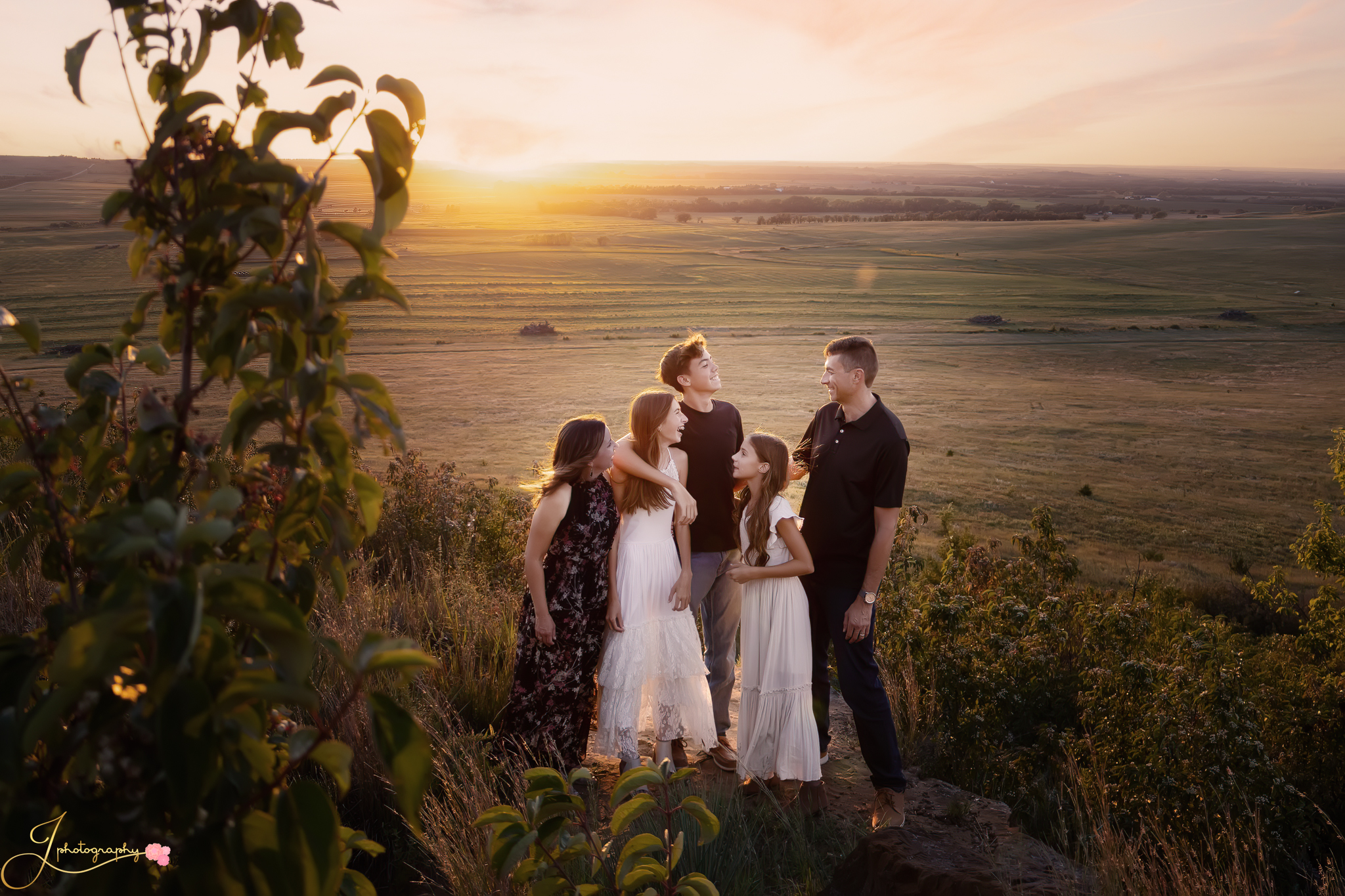 Family with five children sitting together in a grassy field