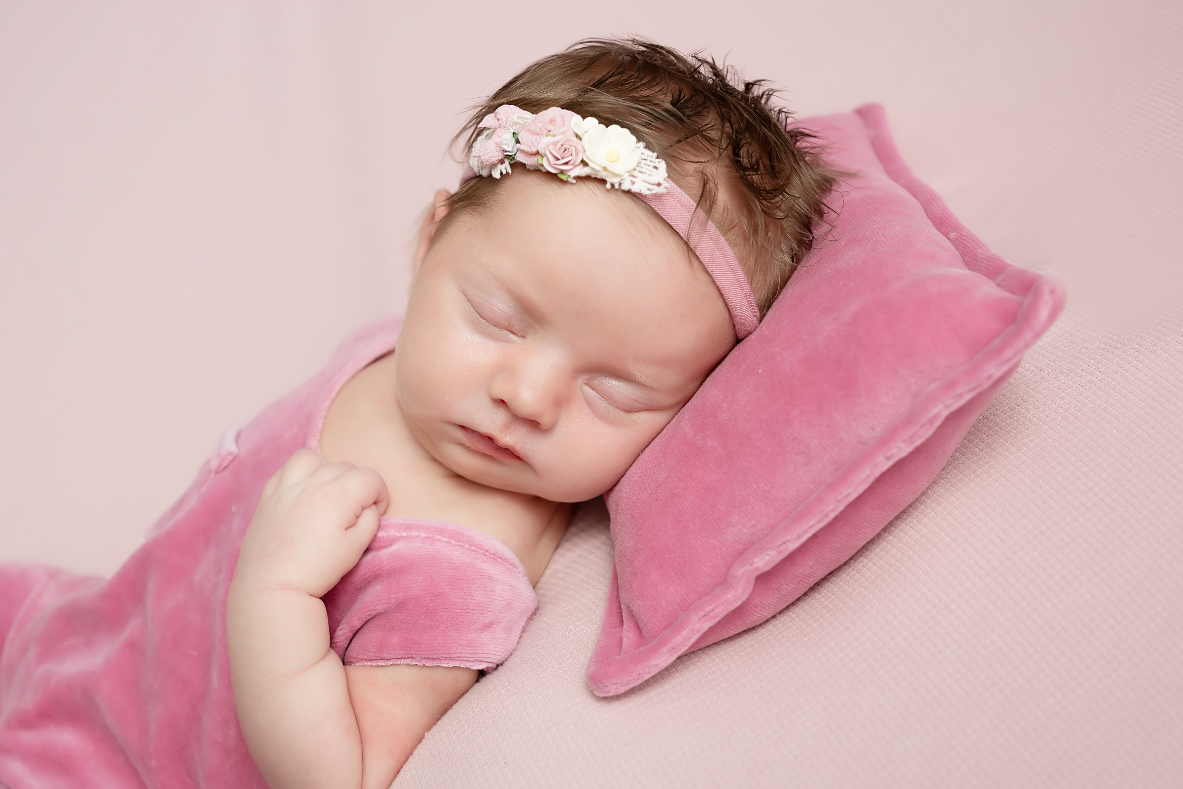 Newborn baby in a blue outfit resting in a basket with a navy blanket